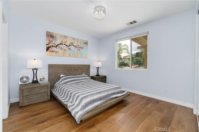 bedroom featuring visible vents, baseboards, and wood finished floors