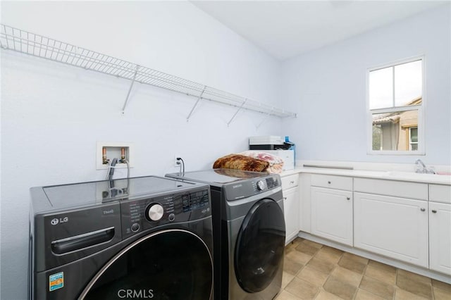 clothes washing area with a sink, cabinet space, and washing machine and dryer