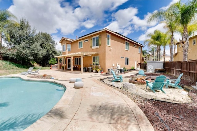 back of property featuring fence, a fenced in pool, a fire pit, and a patio area