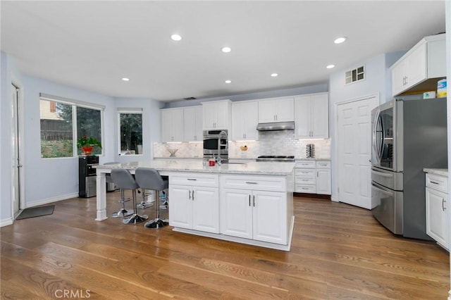 kitchen with under cabinet range hood, white cabinetry, appliances with stainless steel finishes, and visible vents