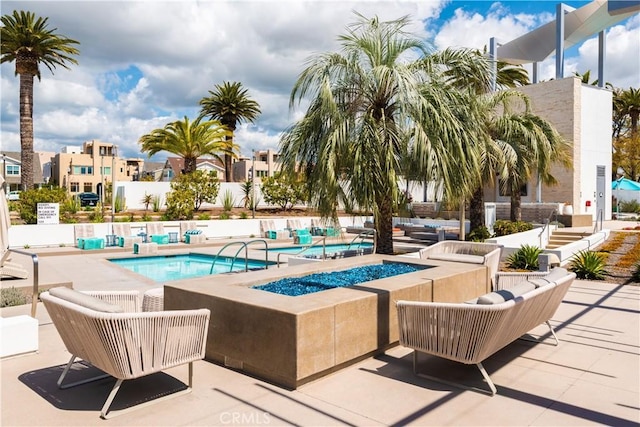 view of swimming pool with a patio, a pool, and an outdoor living space with a fire pit