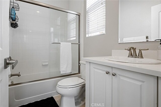 bathroom featuring toilet, enclosed tub / shower combo, and vanity