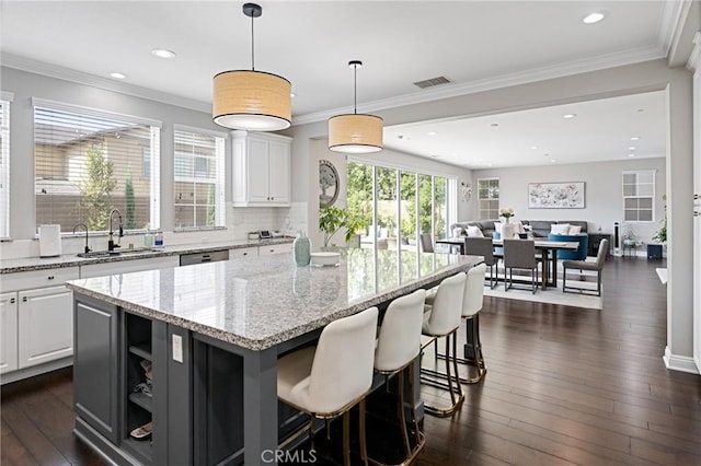 kitchen featuring a kitchen island, visible vents, dark wood finished floors, a sink, and white cabinetry
