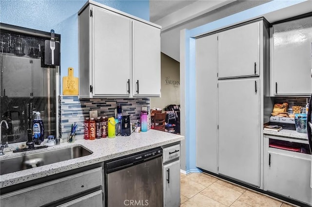 kitchen featuring stainless steel dishwasher, decorative backsplash, light tile patterned flooring, white cabinets, and a sink