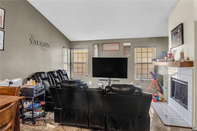 tiled living room with a tiled fireplace, plenty of natural light, and vaulted ceiling