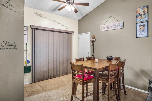 dining space with light tile patterned flooring, a textured ceiling, a ceiling fan, baseboards, and vaulted ceiling