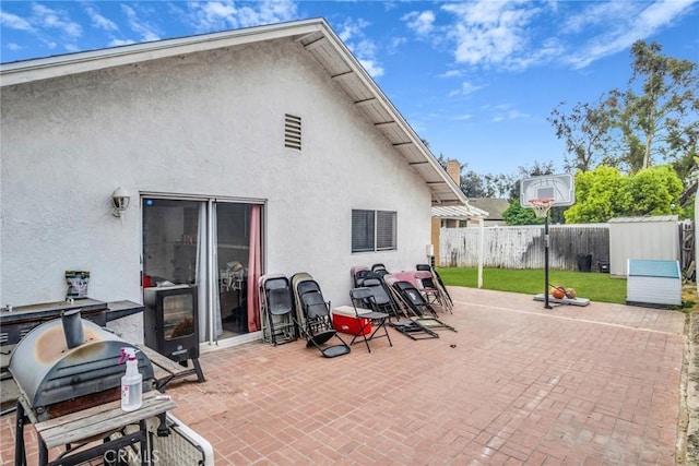 back of house with a fenced backyard, a patio, and stucco siding