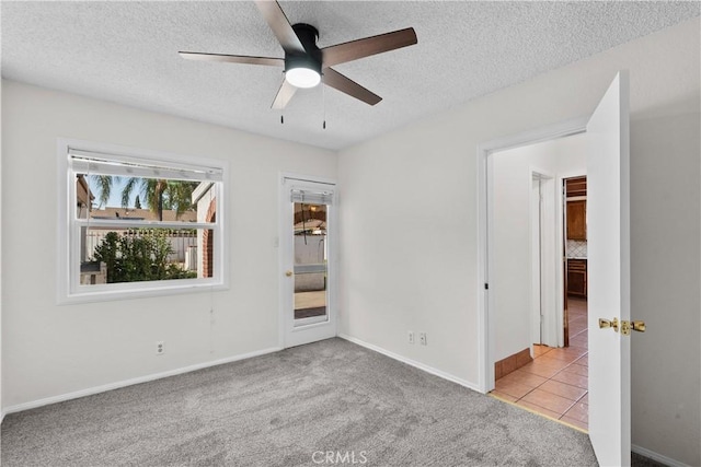 unfurnished bedroom with carpet flooring, a textured ceiling, and baseboards