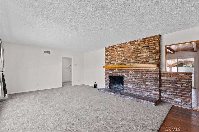 unfurnished living room with baseboards, a textured ceiling, visible vents, and a fireplace
