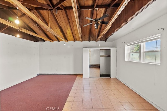 tiled empty room featuring baseboards, a ceiling fan, lofted ceiling with beams, and wooden ceiling