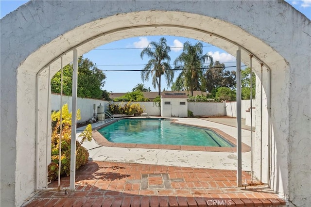 view of pool featuring a storage shed, a fenced in pool, an outdoor structure, a fenced backyard, and a patio