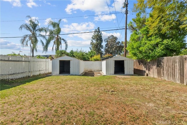 view of yard with a fenced backyard, a storage unit, and an outbuilding
