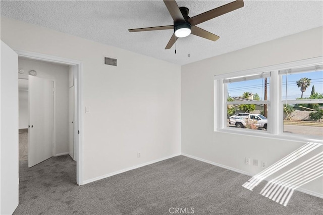 spare room featuring carpet floors, a ceiling fan, a textured ceiling, and visible vents