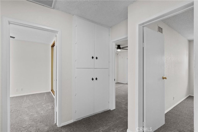 corridor with carpet floors, a textured ceiling, and visible vents