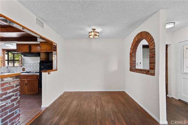 unfurnished dining area with a sink, dark wood-style flooring, a textured ceiling, and visible vents