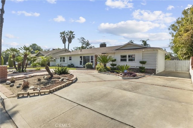 single story home featuring fence, curved driveway, and a chimney