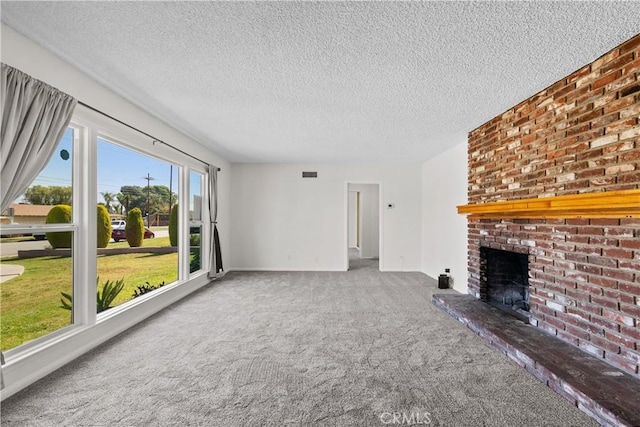 unfurnished living room with a textured ceiling, visible vents, a brick fireplace, carpet floors, and baseboards