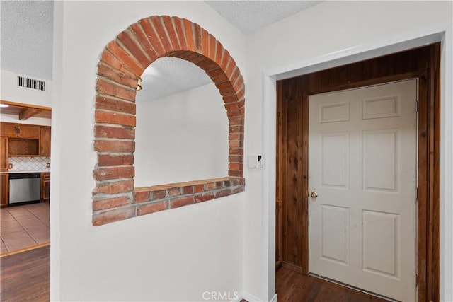 hallway featuring visible vents, arched walkways, a textured ceiling, and dark wood-style floors