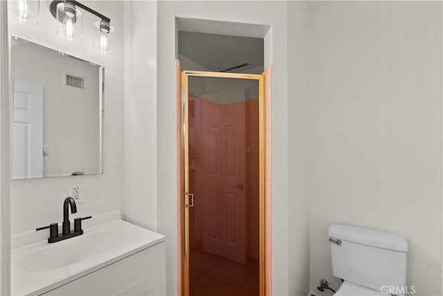 bathroom featuring toilet, a shower with door, visible vents, and vanity