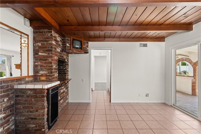 spare room featuring visible vents, light tile patterned flooring, wooden ceiling, and beamed ceiling