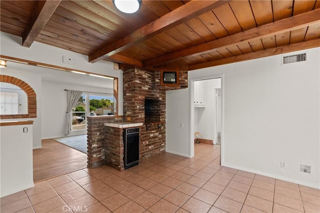 interior space featuring tile countertops, light tile patterned floors, beamed ceiling, visible vents, and wood ceiling