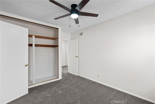 unfurnished bedroom with a closet, dark carpet, a textured ceiling, and visible vents