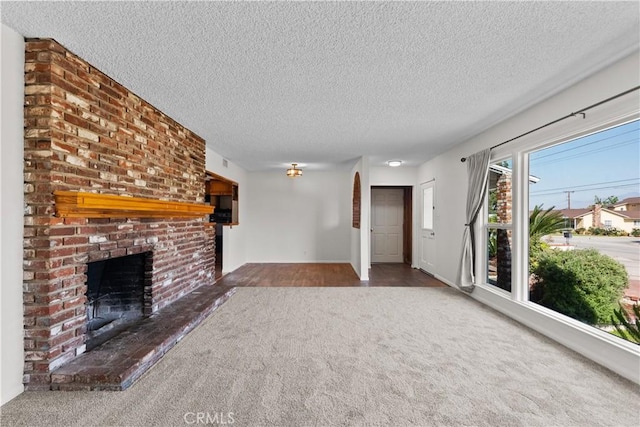 unfurnished living room with carpet flooring, a textured ceiling, and a fireplace