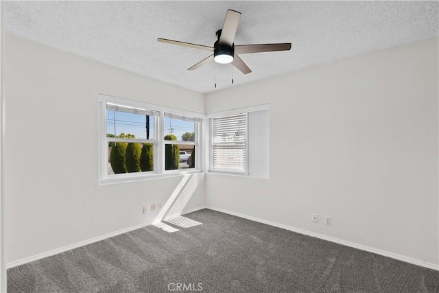 empty room with baseboards, a ceiling fan, dark carpet, and a textured ceiling