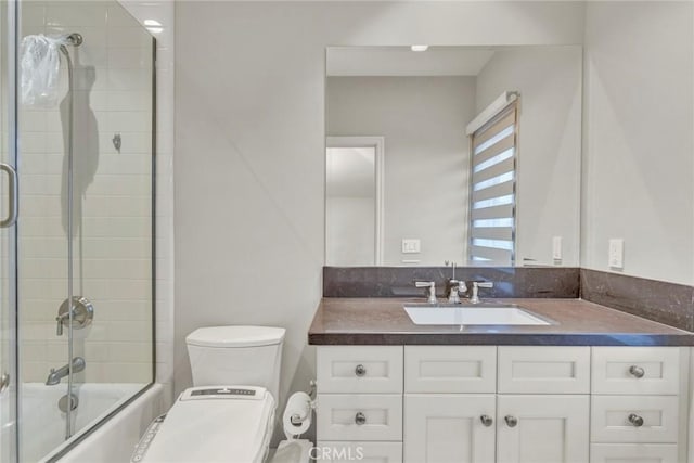 bathroom featuring vanity, toilet, and shower / bath combination with glass door