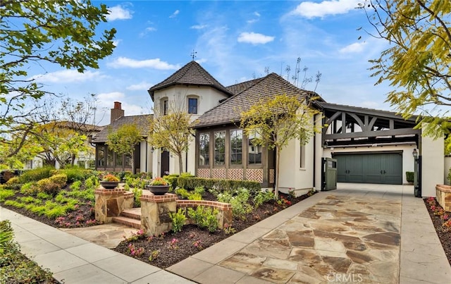 view of front of house with concrete driveway, an attached garage, a chimney, and stucco siding