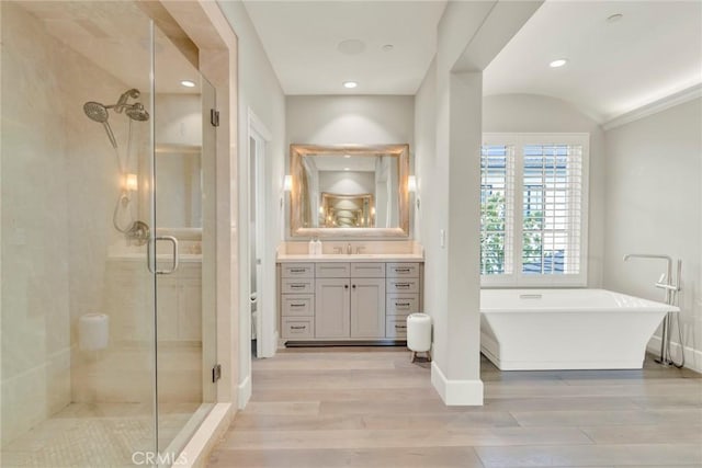 bathroom with vanity, a freestanding bath, wood finished floors, and a stall shower