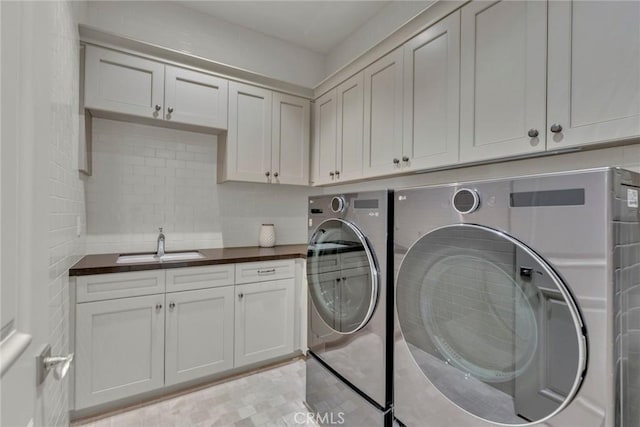 laundry room with cabinet space, separate washer and dryer, and a sink