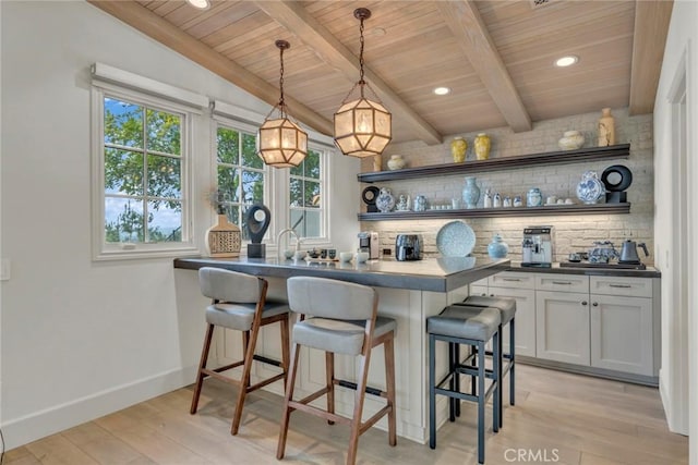 bar featuring light wood finished floors, baseboards, decorative light fixtures, tasteful backsplash, and wood ceiling