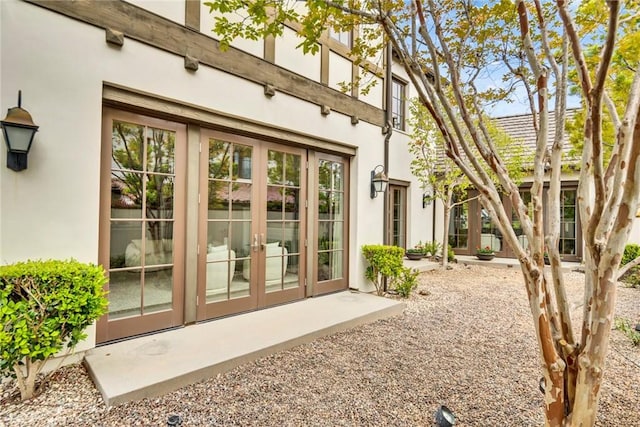 view of exterior entry featuring french doors and stucco siding