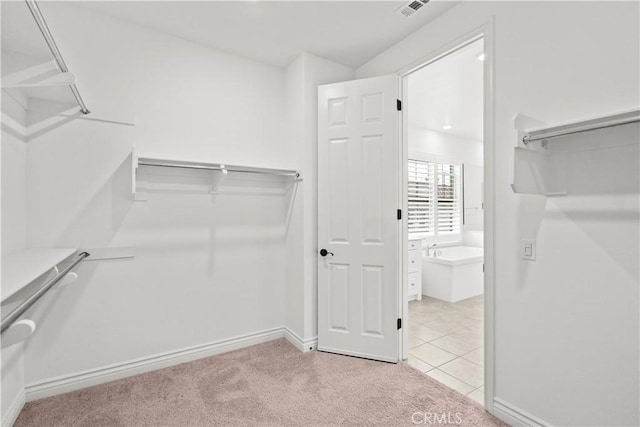 walk in closet with light colored carpet, visible vents, and light tile patterned floors