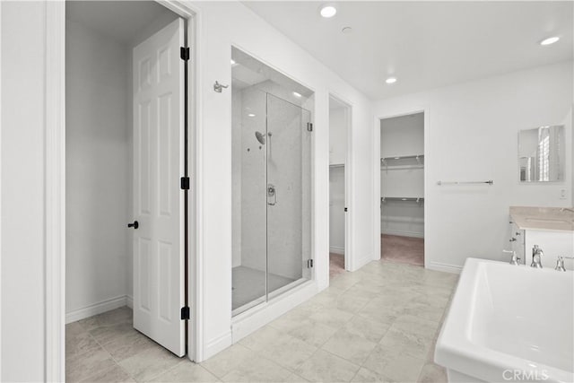 bathroom featuring a stall shower, vanity, baseboards, a spacious closet, and recessed lighting