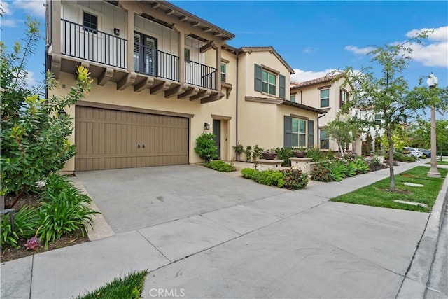 mediterranean / spanish-style home with a garage, stucco siding, concrete driveway, and a balcony