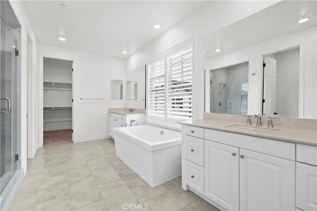 full bathroom with a freestanding tub, recessed lighting, two vanities, a shower stall, and a sink