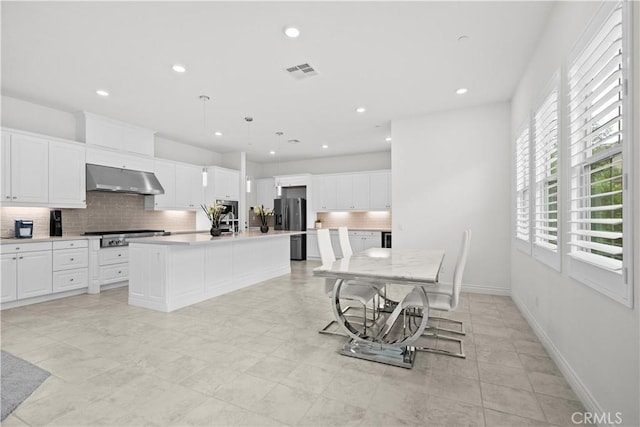 kitchen featuring white cabinets, appliances with stainless steel finishes, backsplash, under cabinet range hood, and visible vents