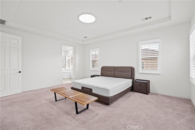 carpeted bedroom with visible vents, baseboards, a tray ceiling, and multiple windows