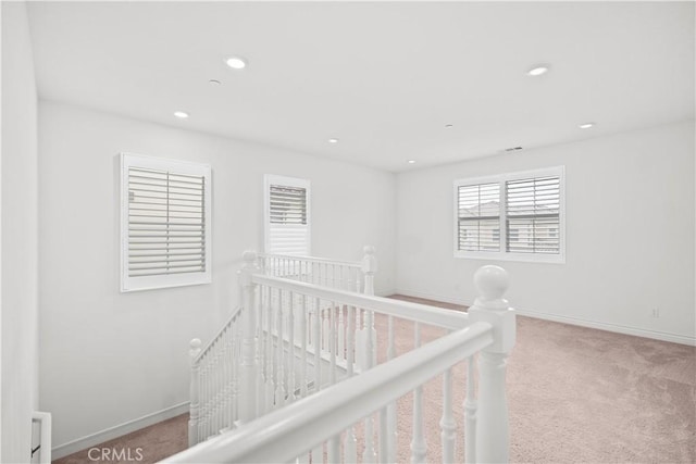 interior space featuring carpet floors, recessed lighting, baseboards, and an upstairs landing