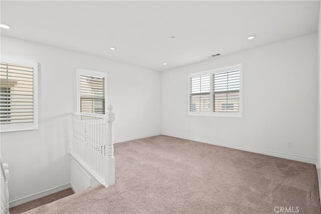 carpeted empty room featuring visible vents, recessed lighting, and baseboards