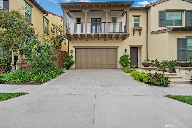 view of front of property featuring a garage, stucco siding, a balcony, and driveway