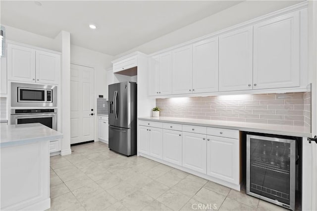 kitchen featuring light countertops, appliances with stainless steel finishes, white cabinets, and beverage cooler