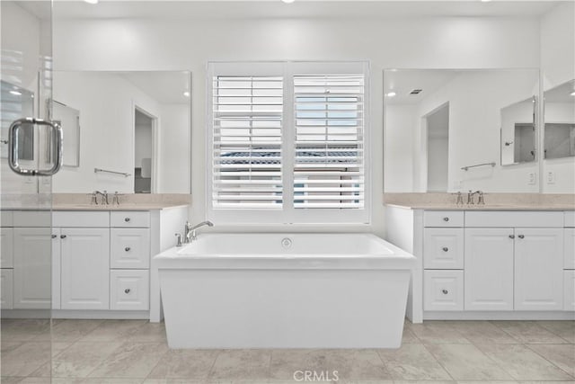 full bath with a freestanding bath, two vanities, and a sink