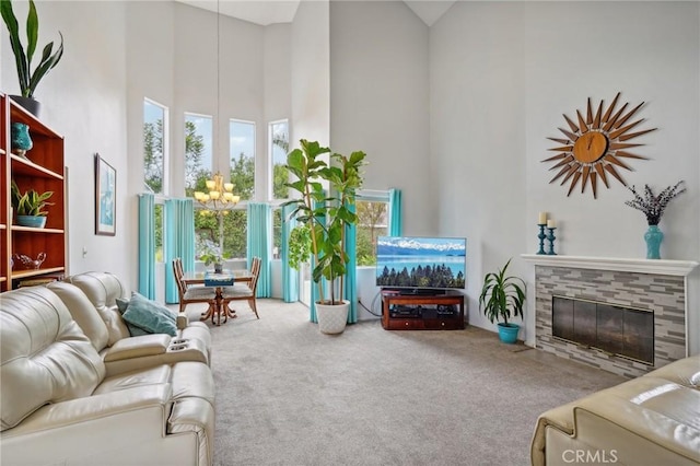 carpeted living area featuring a towering ceiling, a notable chandelier, and a fireplace
