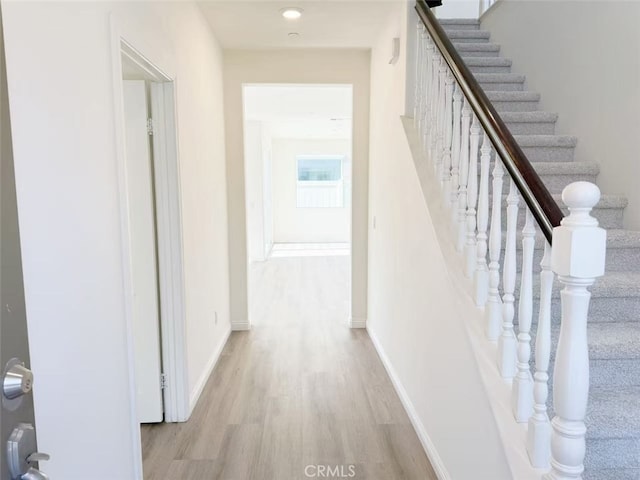 hall featuring stairway, baseboards, and light wood finished floors