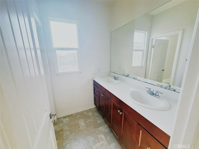 full bathroom featuring double vanity, a healthy amount of sunlight, and a sink