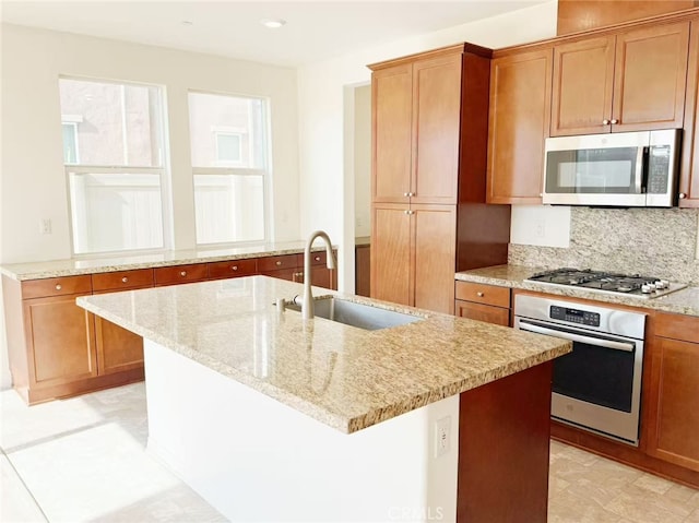 kitchen featuring brown cabinetry, a sink, appliances with stainless steel finishes, and light stone countertops