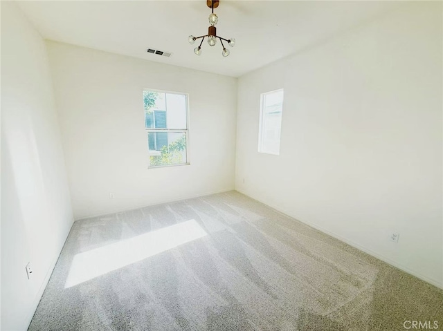 carpeted empty room with a notable chandelier and visible vents